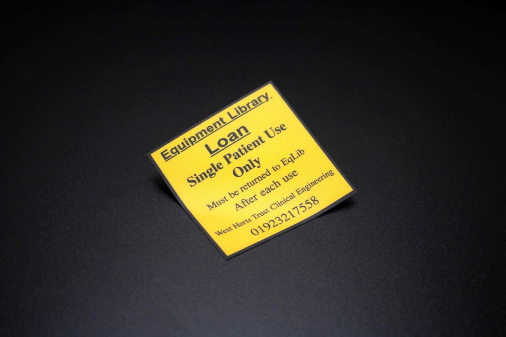 Square yellow plastic medical equipment label with black border and text
